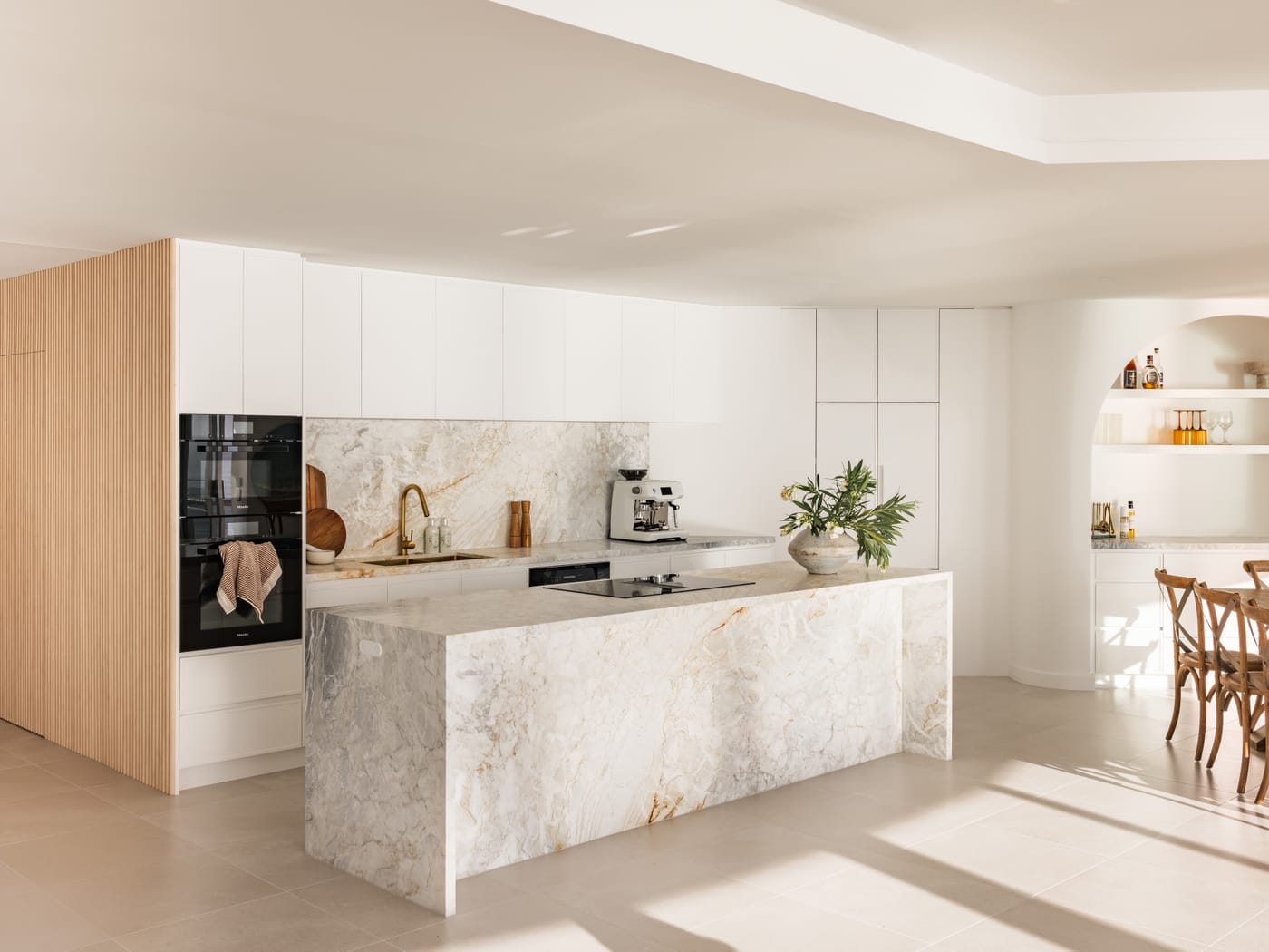 Bright kitchen with a stone waterfall island and oak cabinetry in a Broadbeach renovation - 4D Cabinetry