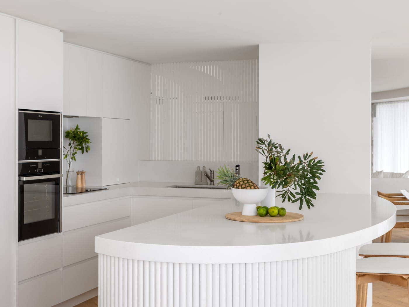 White apartment kitchen with a fluted curved island in a Surfers Paradise renovation - 4D Cabinetry