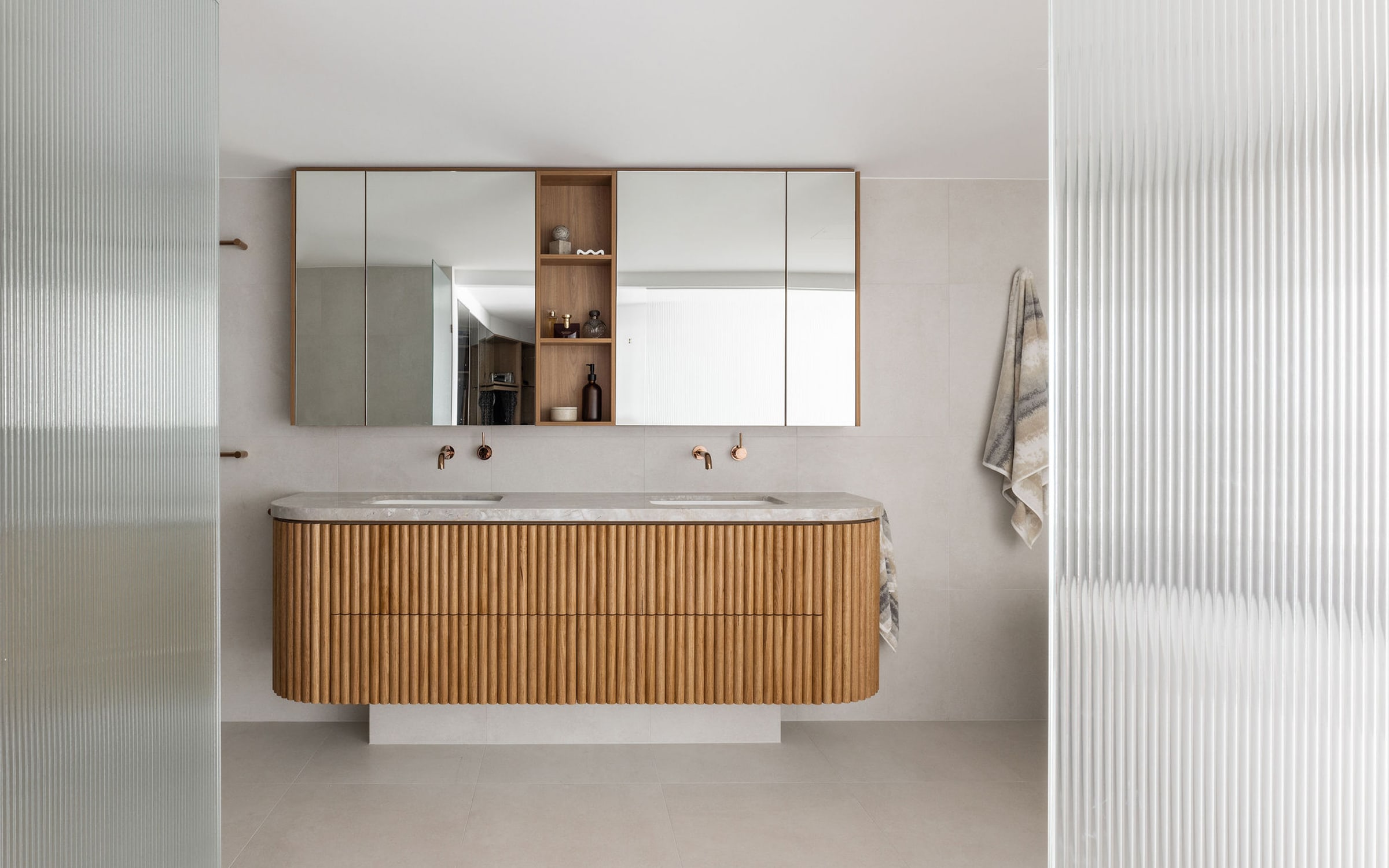Custom curved fluted-oak bathroom vanity with a stone top on the Gold Coast